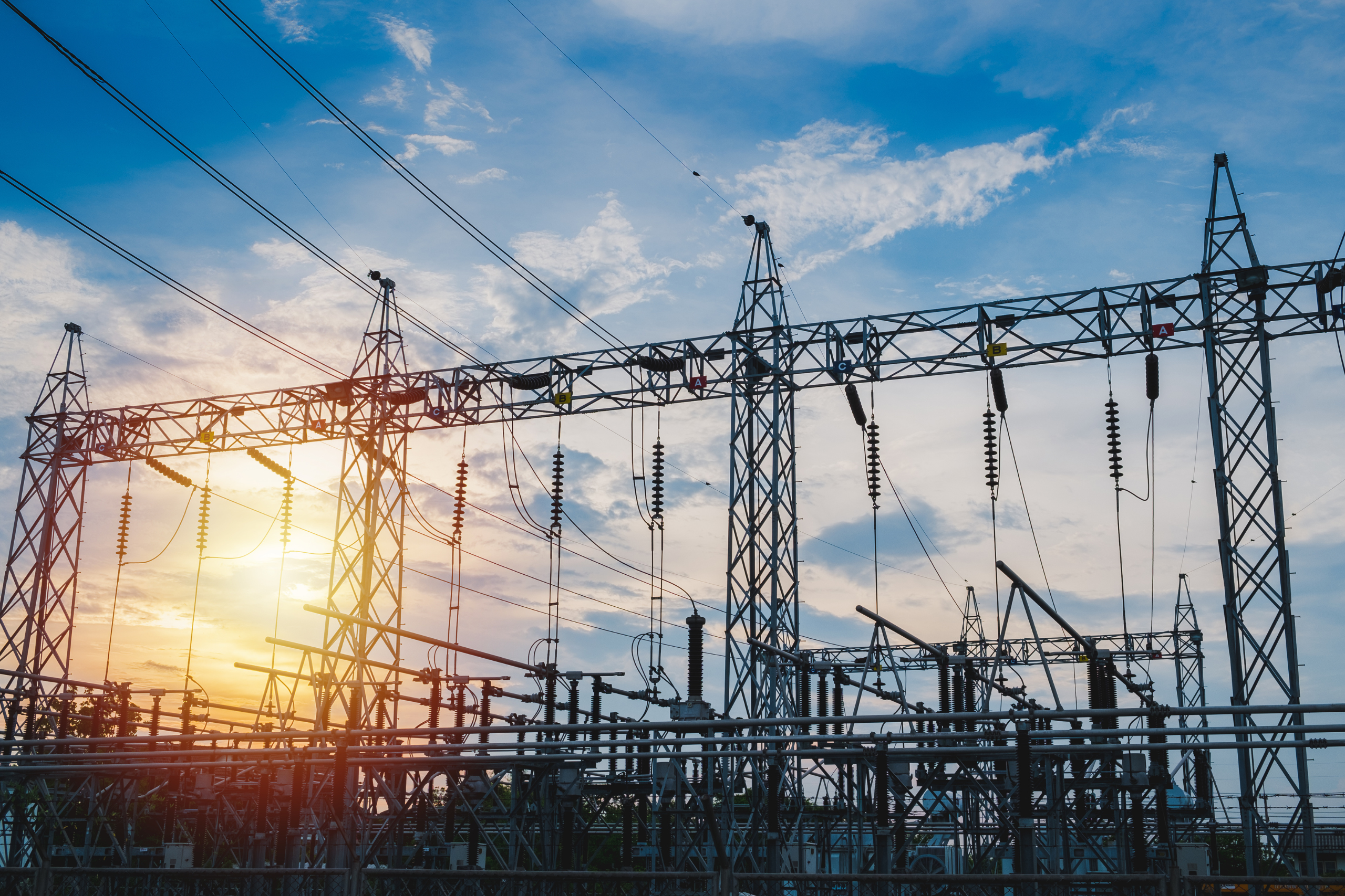 Hoogspanningsstation met elektriciteitskabels tijdens zonsondergang